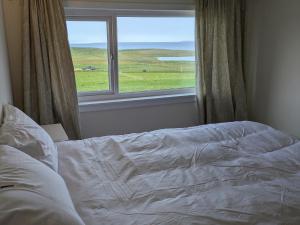 an unmade bed in a bedroom with a window at Rousay&nbspCottage in Orkney