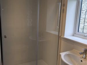 a shower with a glass door next to a sink at Lower Cottage in Orkney