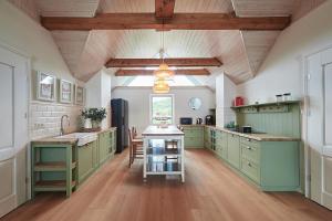 a large kitchen with green cabinets and a table at Królowa Kaczek - własna plaża, pomost, sauna z widokiem na wodę i sala warsztatowa in Sorkwity