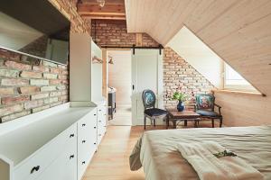 a bedroom with a brick wall and a bed and chairs at Królowa Kaczek - własna plaża, pomost, sauna z widokiem na wodę i sala warsztatowa in Sorkwity