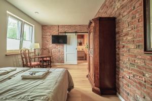 a room with a bed and a brick wall at Królowa Kaczek - własna plaża, pomost, sauna z widokiem na wodę i sala warsztatowa in Sorkwity