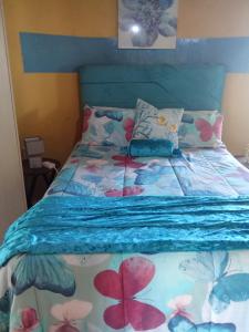 a bed with a blue comforter with flowers on it at Qbela in Phuthaditjhaba