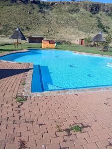 a large blue swimming pool with umbrellas at Qbela in Phuthaditjhaba