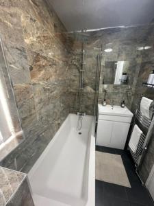 a bathroom with a shower and a tub and a sink at The Wigmore house in Luton +24 photos