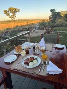 a table with a plate of breakfast food on it at Chamabondo Luxury Tented Camp in Victoria Falls