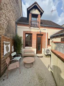 a patio with a table and chairs and a building at Le Nid Arrivé autonome clim wifi linge inclus in Romorantin