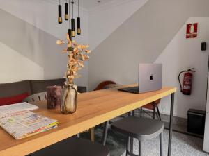 a wooden table with a laptop and a vase with flowers at Hotel Gabriel y Galán in Salamanca