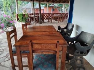 ein Holztisch und einige Stühle und ein Tisch und einige Tische in der Unterkunft Hôtel Bellevue in Natitingou