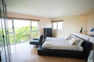 a bedroom with a bed and a black chair at Torres Vedras House in Silveira +21 photos