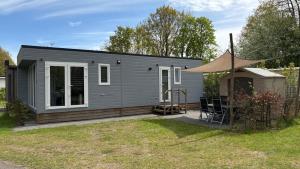 a small grey house with a tent in a yard at Chalet Pallegarste 153 in Mariënberg
