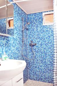 a blue tiled bathroom with a shower and a sink at Villa-Hufeland in Berlin