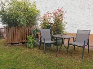 three chairs and a table in a yard with a fence at Ferienwohnung im Erdgeschoss direkt am Rad- und Spazierweg in Silz