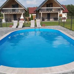 a large blue swimming pool in front of a house at Domki letniskowe Malina 1 in Gawrony