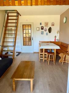 a living room with a table and a staircase at Appartement en bord de lac in Malbuisson