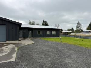 a black building with a gravel driveway in front of it at Luxury Villa Dynskogar Hveragerdi in Hveragerði