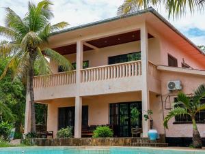a house with a palm tree in front of it at Tradewinds Lodge in Diani Beach