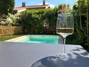 a glass of wine sitting on a table next to a pool at Comme à la maison B and B - 2 chambres et 1 salon in Carcassonne +27 photos