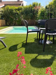 a yard with two chairs and a table next to a pool at Comme à la maison B and B - 2 chambres et 1 salon in Carcassonne