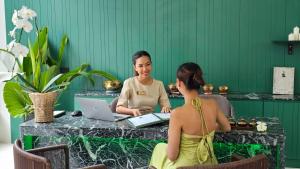 two women sitting at a table with a laptop at GreenLa by Villacarte in Layan Beach +76 photos