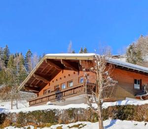 a large wooden house in the snow with a tree at Landhaus Rieder in Mittersill