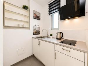 a kitchen with white cabinets and a sink at Turmhotel Rhein-Main - klimatisierte Apartments in Dreieich