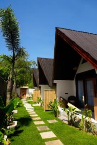 a yard with a house and a palm tree at Asem Bungalows in Kuta Lombok