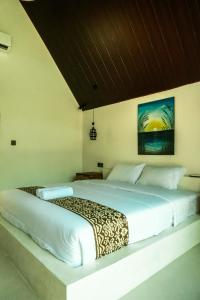 a bedroom with a white bed with a leopard print blanket at Asem Bungalows in Kuta Lombok +15 photos