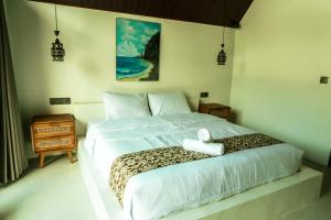 a bedroom with a white bed with a leopard print blanket at Asem Bungalows in Kuta Lombok