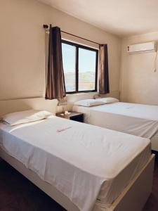 two beds in a room with a window at Arpini Hotel in Rio Grande