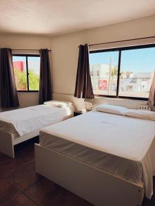 a hotel room with two beds and a window at Arpini Hotel in Rio Grande