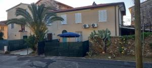 a house with a fence and a blue umbrella at Casa Deanna in Querceta