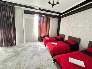 a bedroom with two beds with red sheets and a window at КАРАВАН САРАЙ 15 Венеция in Türkistan