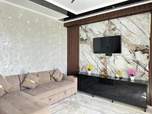 a living room with a couch and a tv on a wall at КАРАВАН САРАЙ 15 Венеция in Türkistan