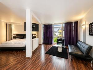 a hotel room with a bed and a couch at Turmhotel Rhein-Main - klimatisierte Apartments in Dreieich +7 photos