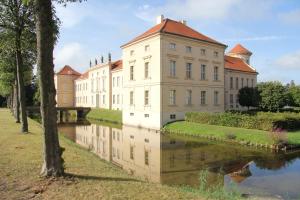 an old building next to a river with a reflection at Ferienhaus Hartmut Löschke in Rheinsberg