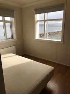 a bedroom with two windows and a bed with a view at Summerhouse by the ocean in Drangsnes