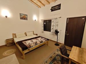 a bedroom with a bed and a table and a window at Ekatma Stays - Farm & Homestay, Kakrighat in Shitlakhet