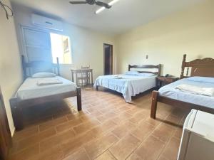 a bedroom with two beds and a wooden floor at Abaeté Palace Hotel in Abaeté