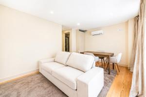 a living room with a white couch and a table at Barcelos Center in Barcelos