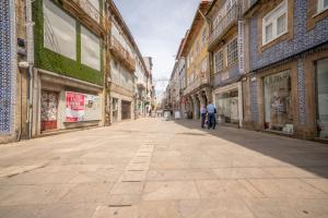 an empty street in a city with people on a bike at Barcelos Center in Barcelos