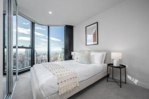 a bedroom with a large white bed and large windows at LaneStay - 2BR Panoramic Views w Pool Spa & Gym in Melbourne