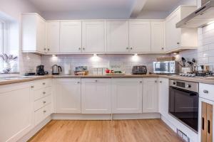 a white kitchen with white cabinets and wooden floors at 4 Bed in Lyndhurst oc-nfl57 in Lyndhurst