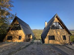 a stone house with two peaked roofs on a hill at Meziad-Panorama in Meziad