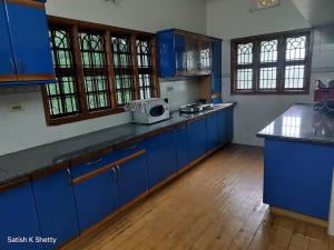 a kitchen with blue cabinets and a microwave on the counter at Rajmata Nivas in Kaup