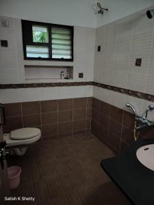 a bathroom with a toilet and a sink and a window at Rajmata Nivas in Kaup