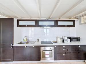 a kitchen with stainless steel appliances and brown cabinets at Spacieux triplex avec vue mer, proche de Monaco, 54 m2 in Cap d'Ail +14 photos