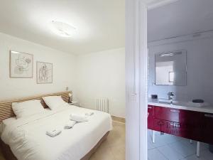 a bedroom with a white bed and a sink at Spacieux triplex avec vue mer, proche de Monaco, 54 m2 in Cap d'Ail