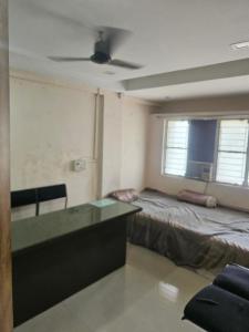 a room with a bed and a desk with a ceiling fan at Homenest Stay in Nashik