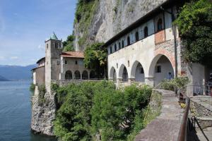 a building on the side of a mountain next to the water at Belmonte Holiday Apartment in Brezzo