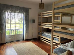 a room with bunk beds with a window and a door at Santa Cruz Surf House by Stoke Travel in A dos Cunhados